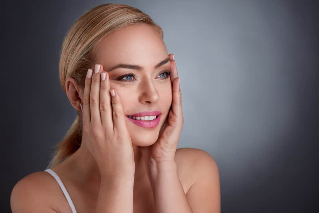 Woman Touching her face after Sculptra Treatment | The Cosmetic Clinic in Greenwich, CT